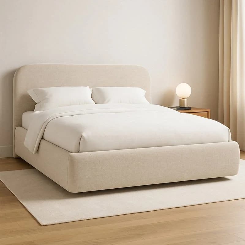 Cama tapizada en tela crema con cabecera de esquinas redondeadas, ropa blanca, buró de madera y lámpara de esfera