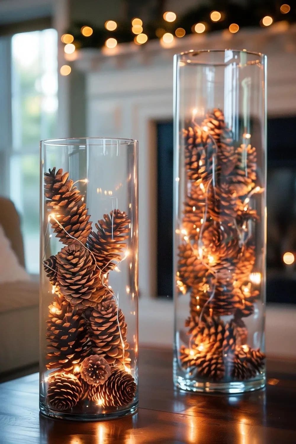 Dos cilindros altos de vidrio llenos de piñas de pino con microluces cálidas sobre una mesa oscura