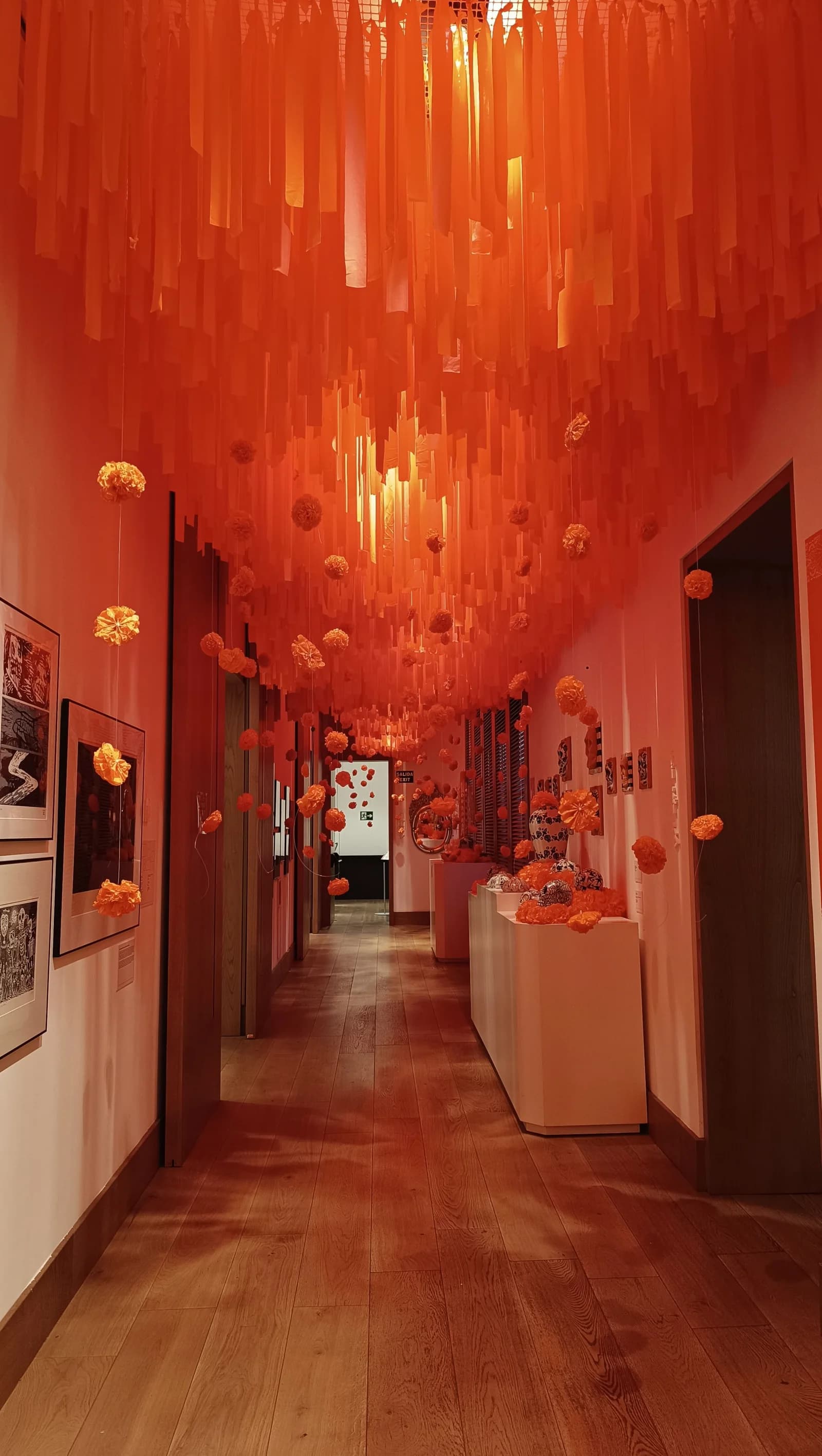 Pasillo con el techo cubierto de tiras largas de papel naranja y flores colgantes