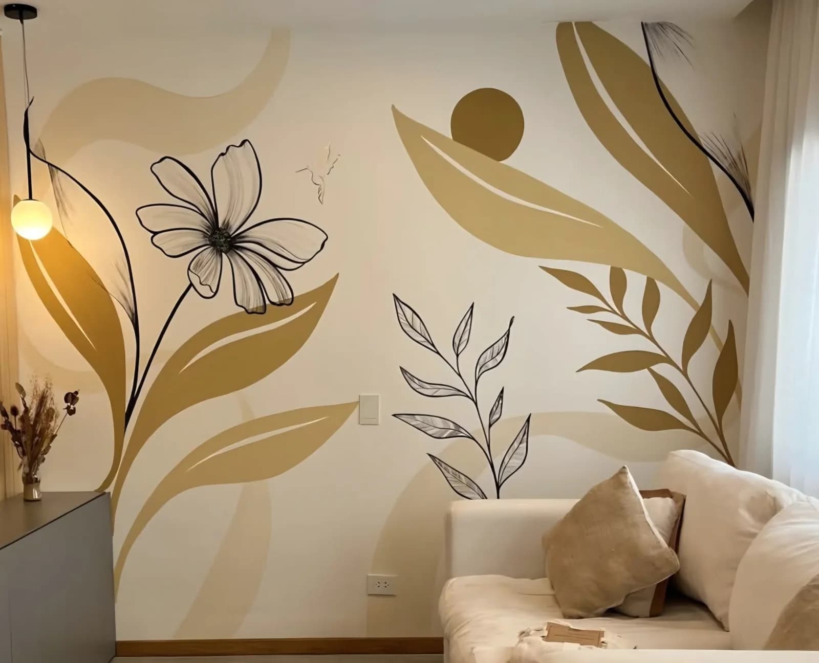 Pared de sala con un mural pintado de hojas grandes en tonos ocre y beige con flores delineadas en negro, junto a un sofá claro