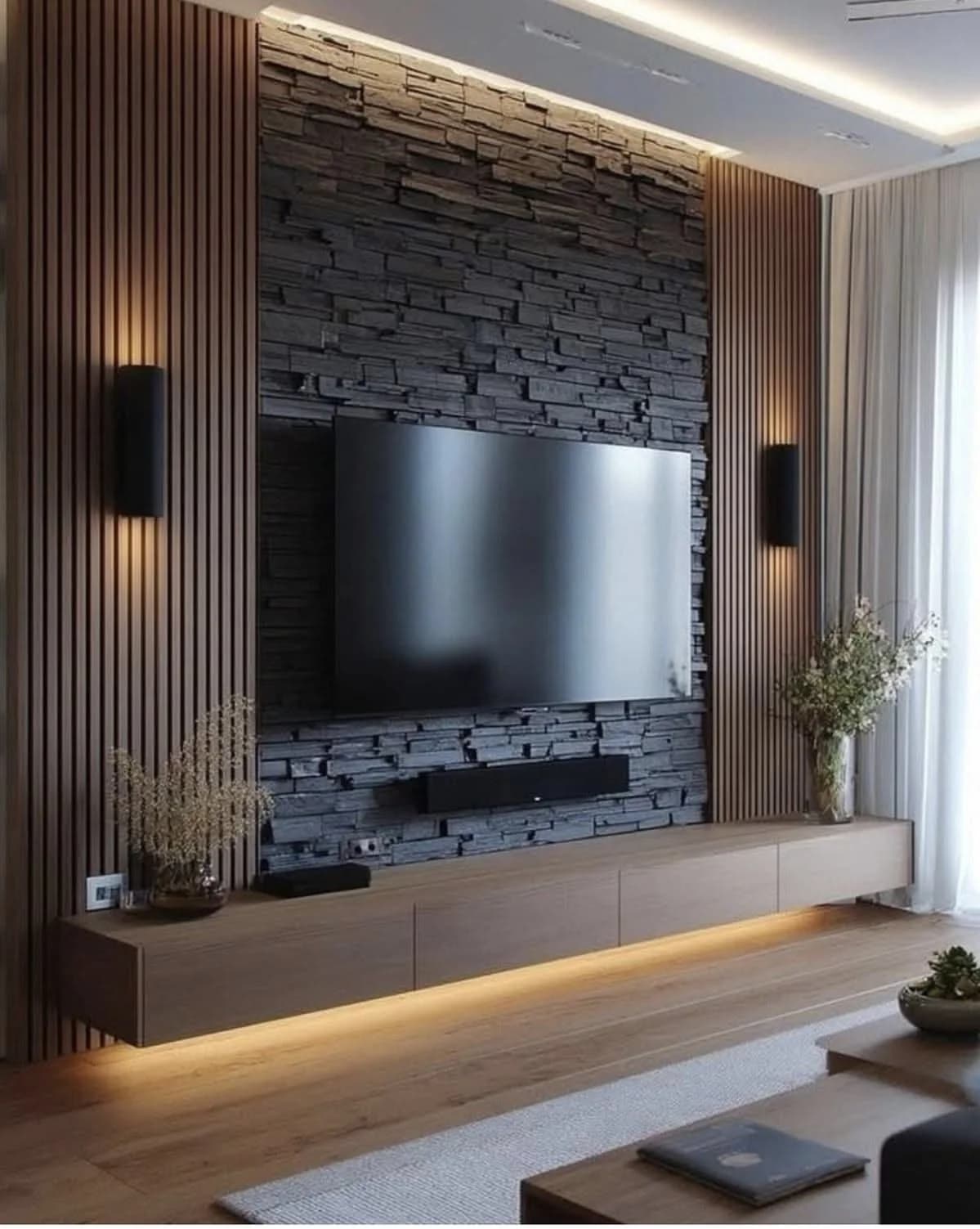 Pared de televisión con piedra laja negra al centro entre dos franjas de lambrín de madera, apliques negros y un mueble flotante con luz debajo